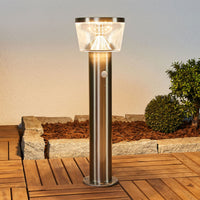 Anjo Solar Pedestal Light lit at dusk beside a garden border
