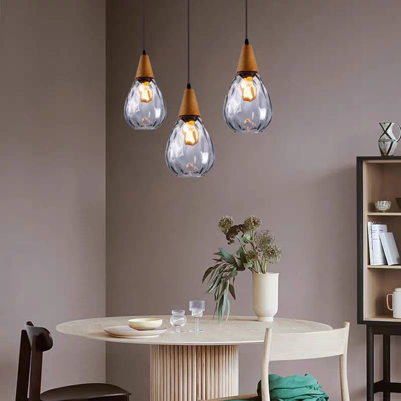 Three Drova clear glass teardrop pendants hung at staggered heights above a round dining table