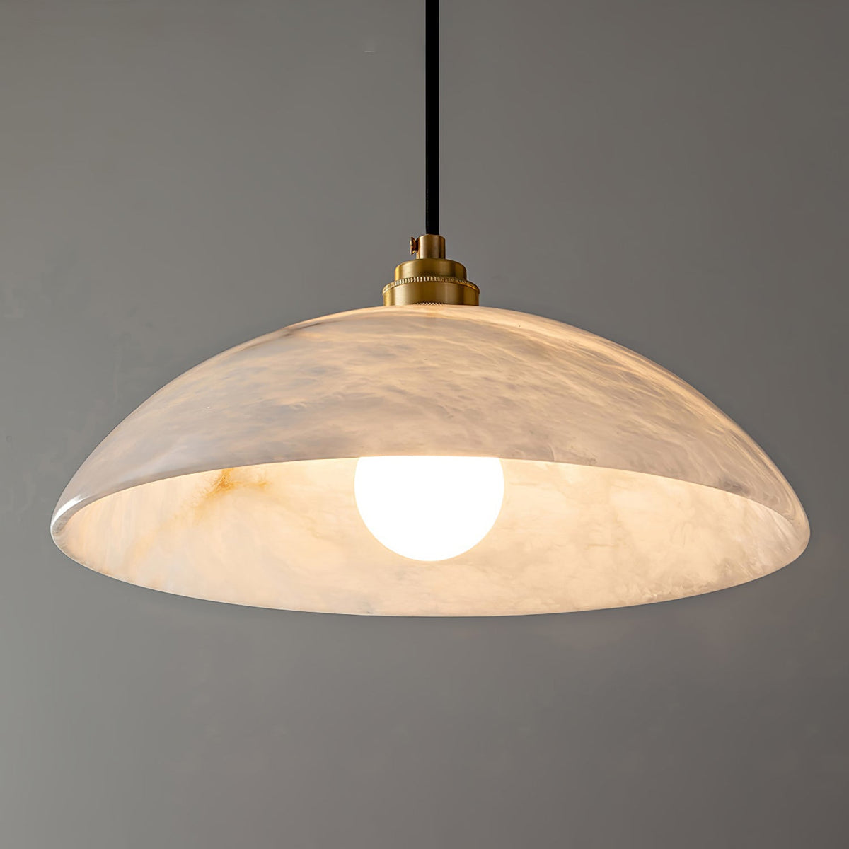 Close view of the lit Delo pendant showing alabaster veining glowing through the stone dome