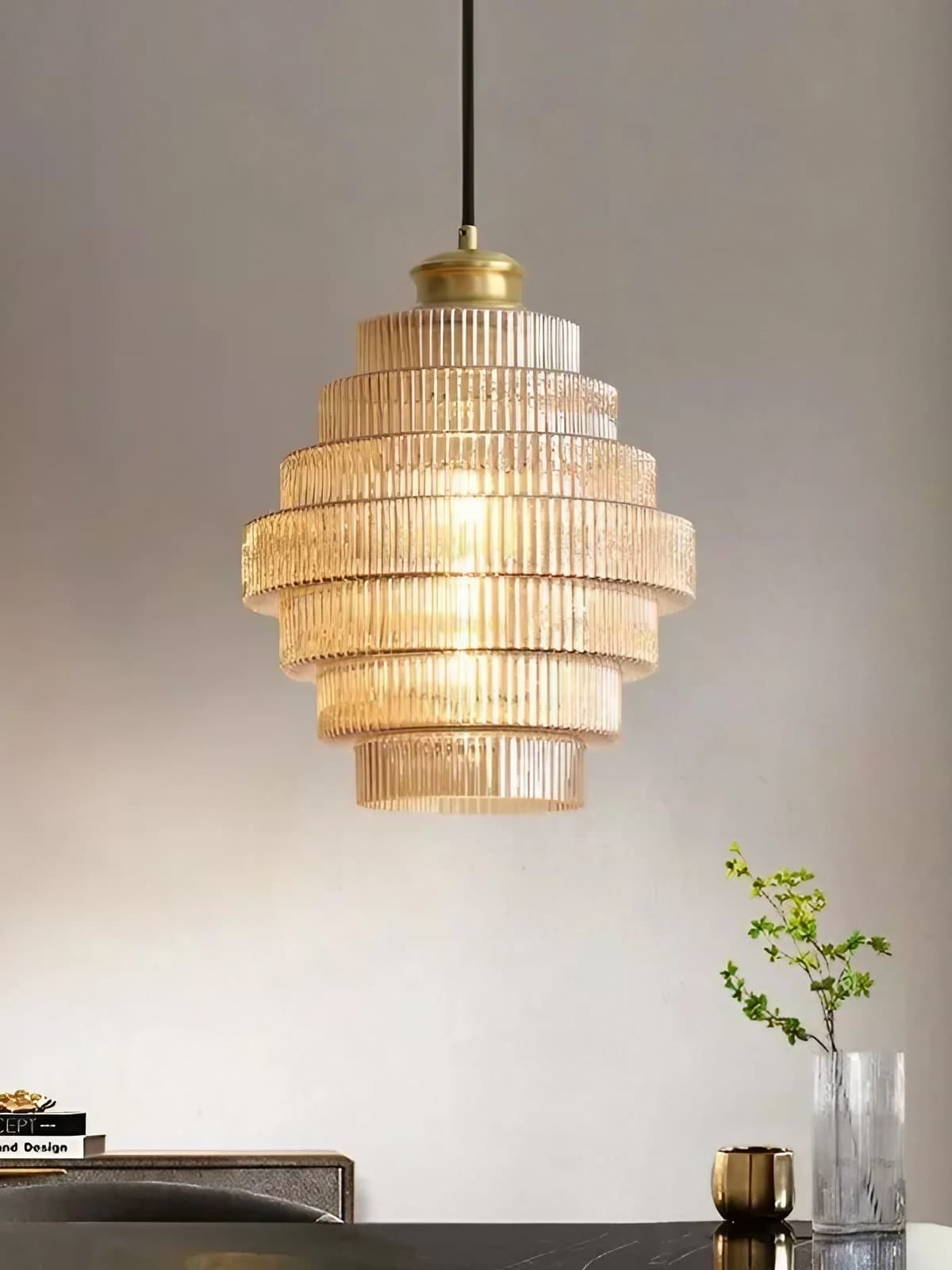Idra amber glass pendant light lit against a plain pale wall above a dark sideboard