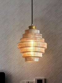 Idra amber glass pendant light lit against a textured plaster wall