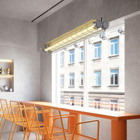 Arsen linear bar pendant light lit above a long counter in a concrete-walled room