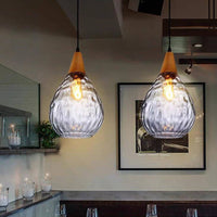 Two Drova clear glass pendant lights lit above a bar counter