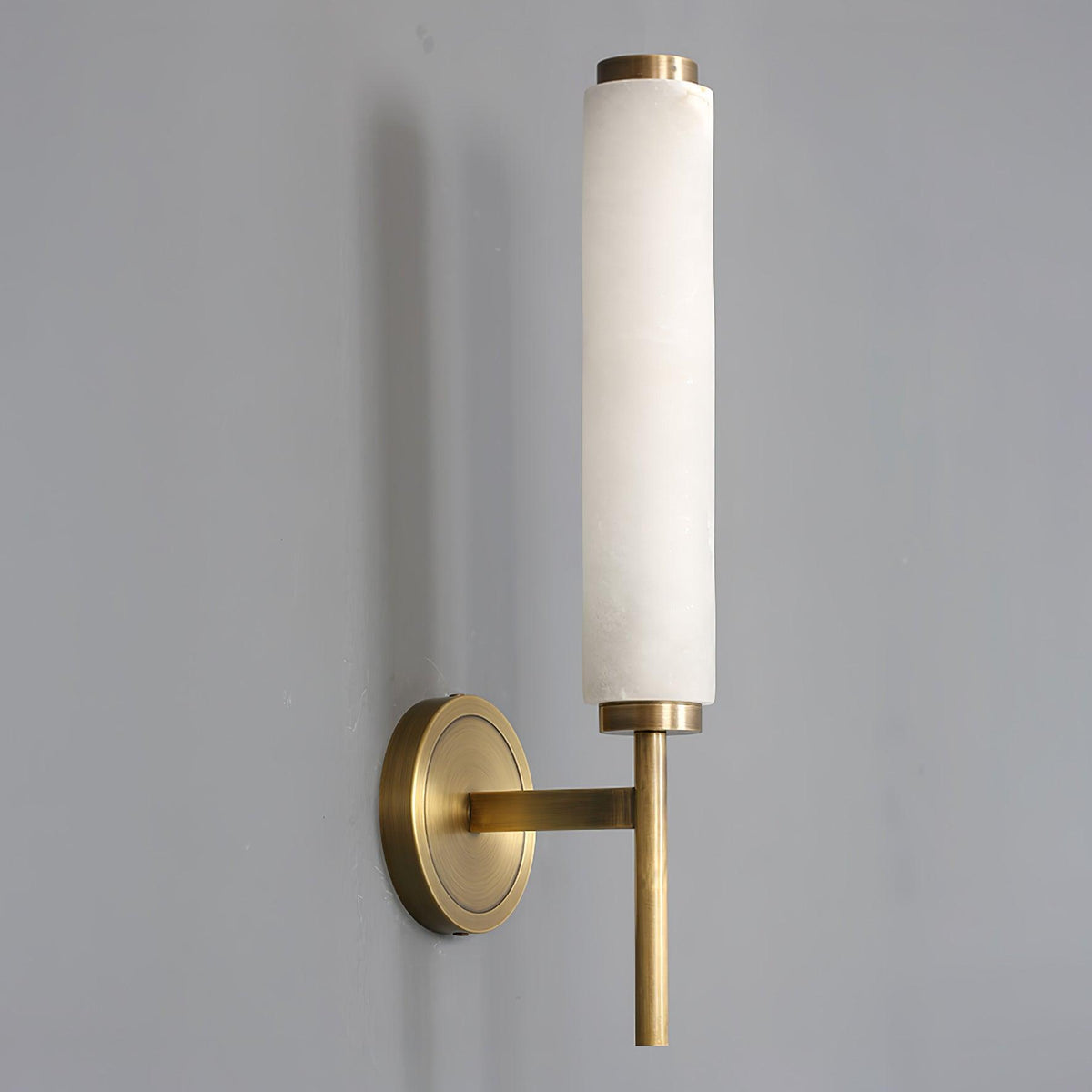 Angled view of the Jerno brass and alabaster sconce mounted on a grey wall