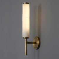 Jerno alabaster wall light lit on a grey wall showing the warm glow through the stone
