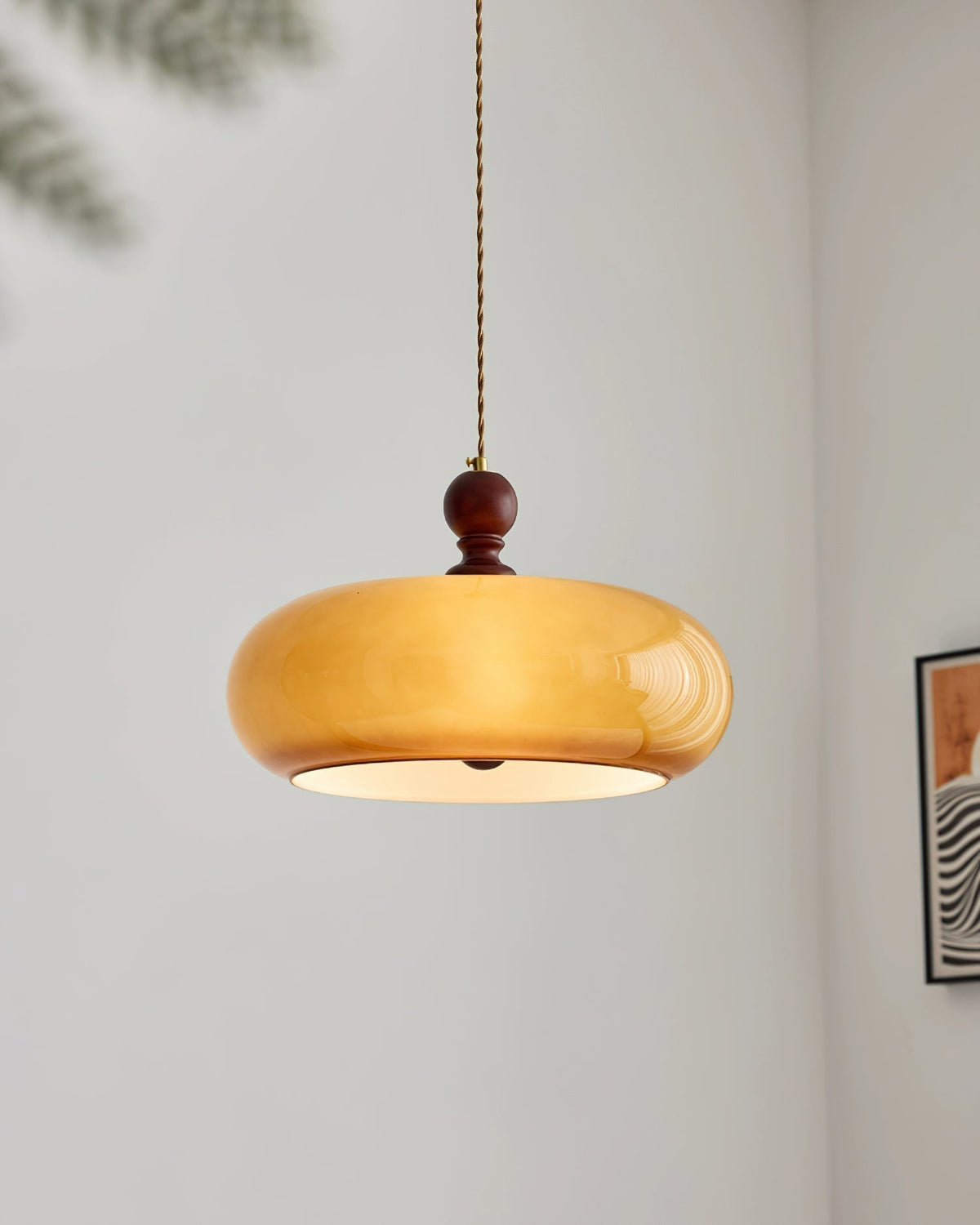 Halvo pendant light switched on, showing the pale diffuser disc across the base of the amber glass shade