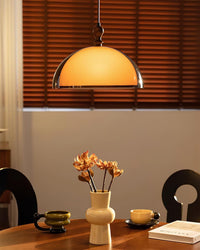 Pomera amber dome pendant lit above a dining table beside a window