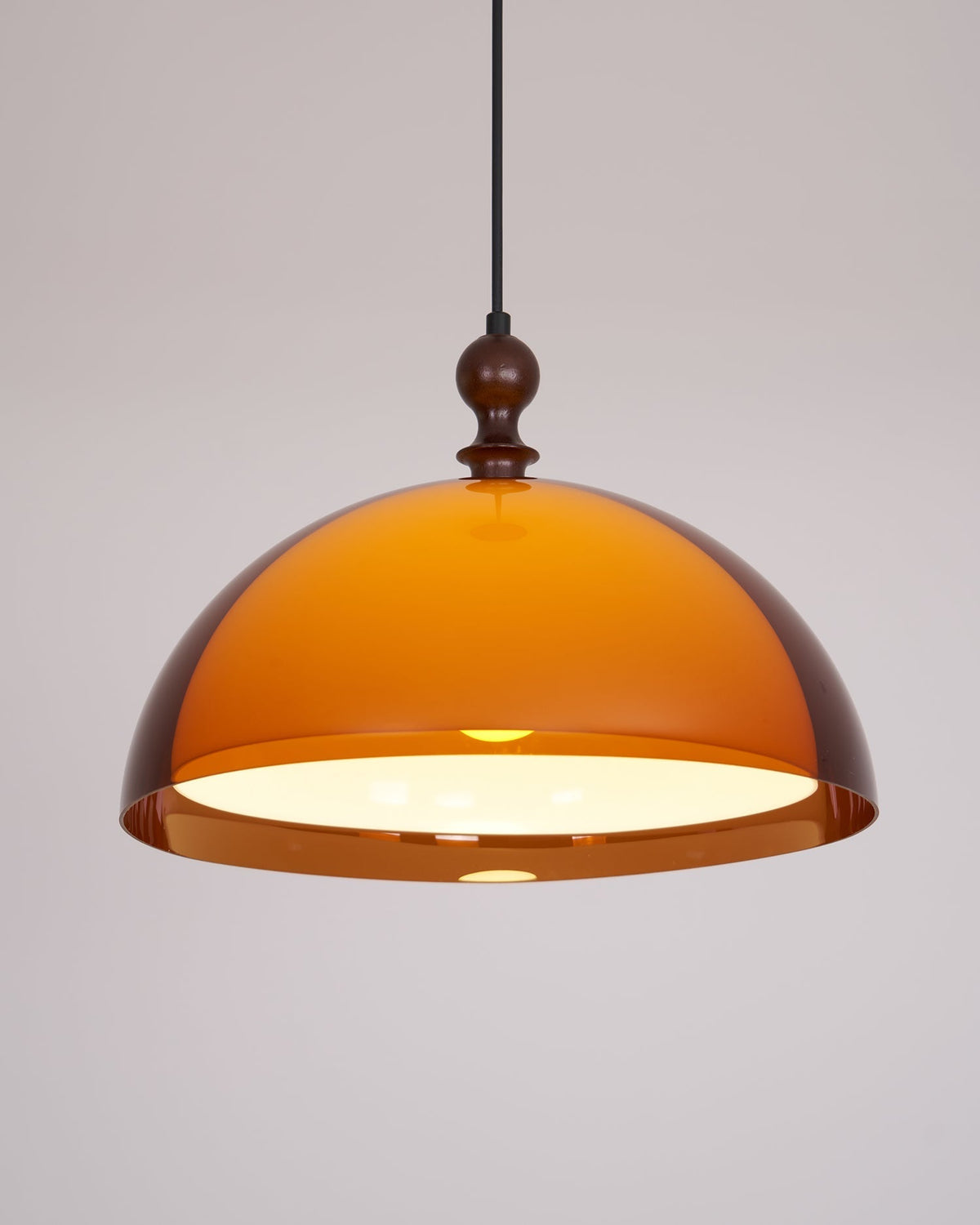 Pomera pendant lit against a plain background showing the honey tone of the amber acrylic dome