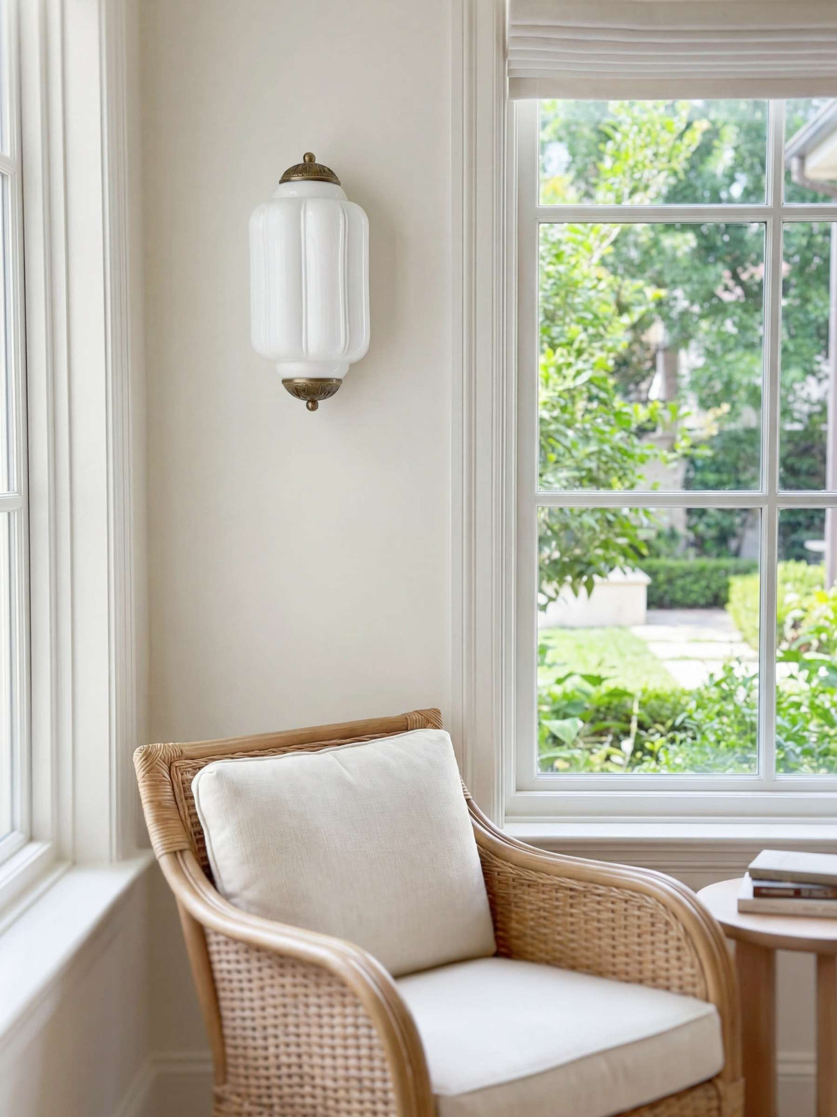 Faro Flush Milk Glass Wall Light mounted beside a window above a rattan armchair