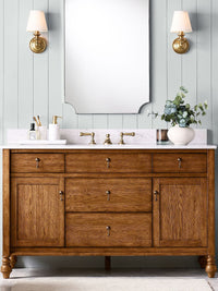 Pair of Ruva brass wall lights either side of a mirror above a wooden vanity