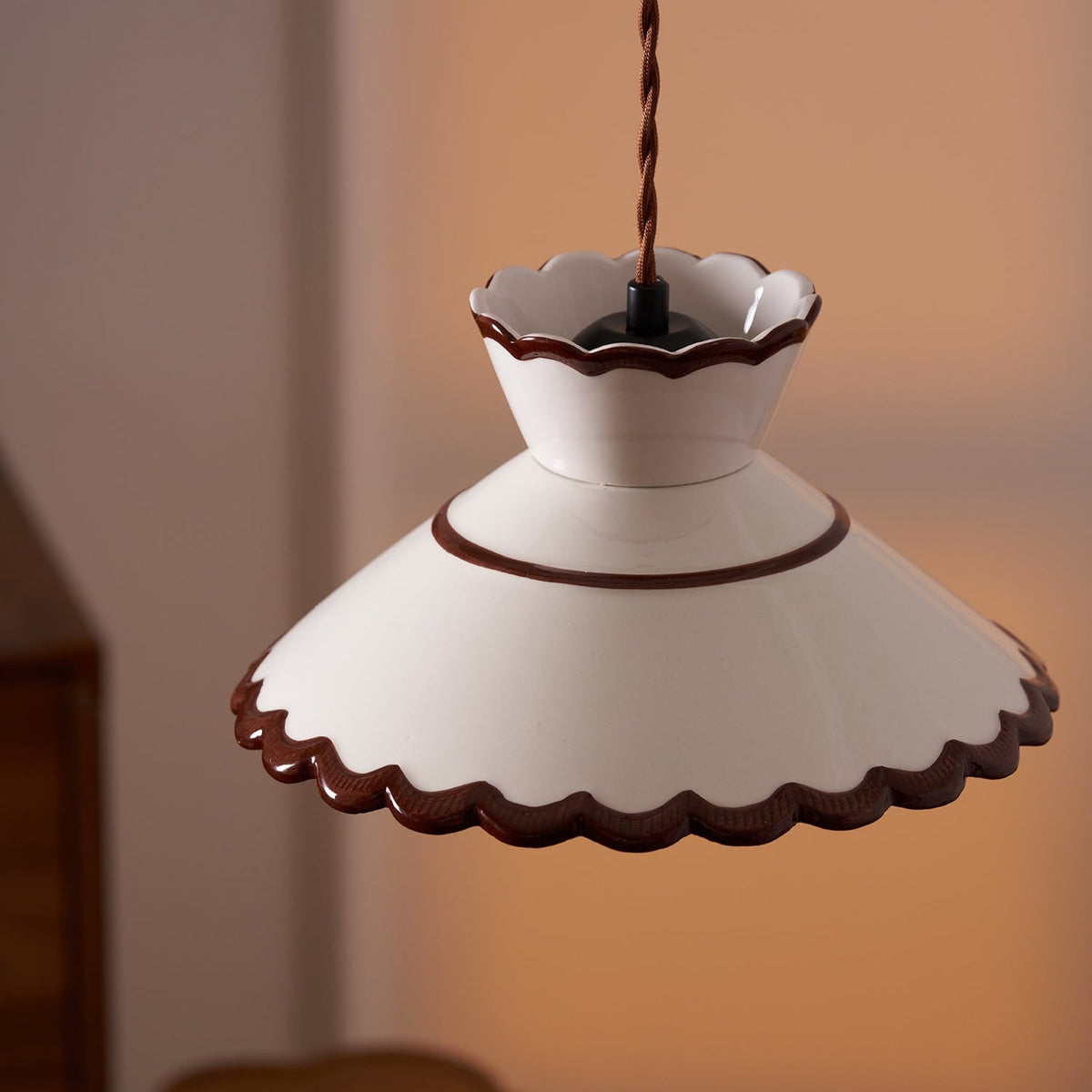 Angled view of the Wenna pendant showing the brown rim line and scalloped edge
