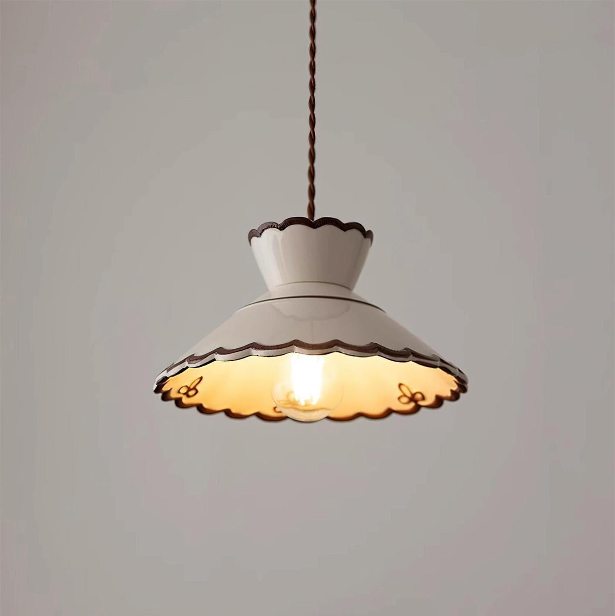 Wenna ceramic pendant light switched on against a plain pale wall