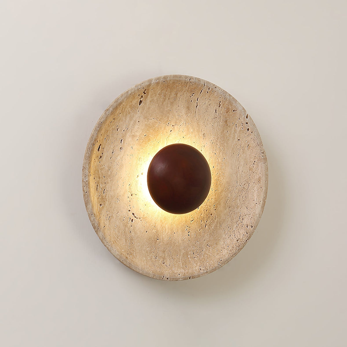 Close view of the Sunda Travertine Wall Light lit on a pale wall, showing the pitted travertine face