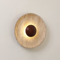 Close view of the Sunda Travertine Wall Light lit on a pale wall, showing the pitted travertine face