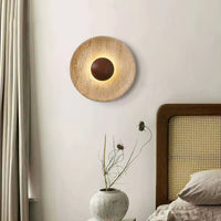 Sunda Travertine Wall Light mounted above a bedside table with a rattan headboard
