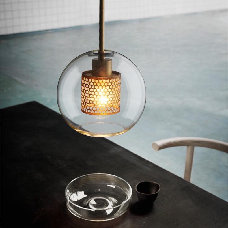Hesso gold globe pendant hanging above a dark dining table