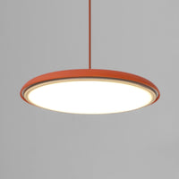 Close view of the Tarvo orange disc pendant lit, showing the acrylic diffuser across the underside