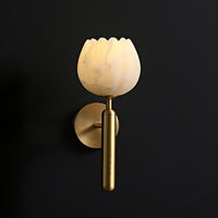Pellora petal wall light lit against a dark charcoal wall showing the warm alabaster glow