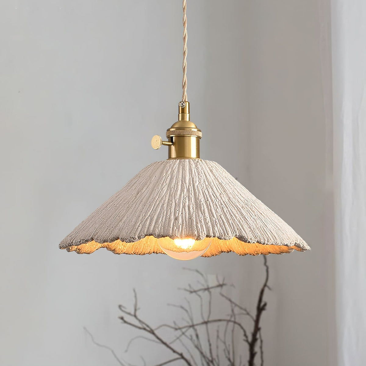Plavo cement pendant lit beside a linen curtain and a branch arrangement