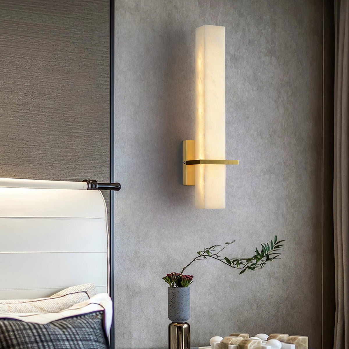 Ritto Alabaster Column Wall Light glowing warm beside a bed with a linen throw