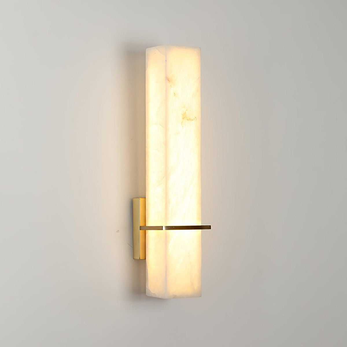 Ritto Alabaster Column Wall Light lit on a pale wall showing the alabaster veining glowing through