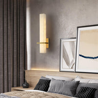 Ritto Alabaster Column Wall Light lit above a bedside table with framed prints