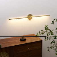 Rodo gold linear wall light glowing above a walnut sideboard