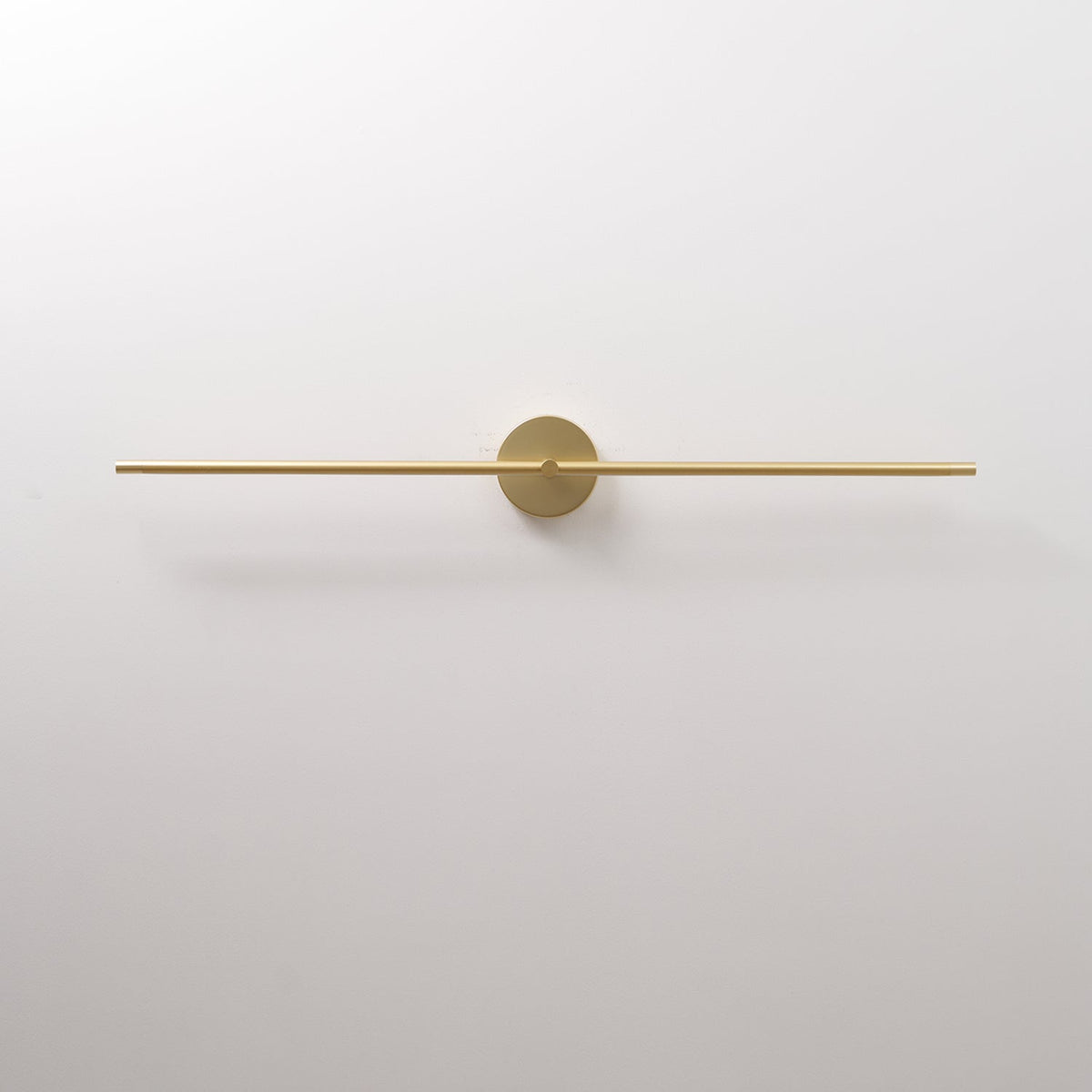 Rodo linear wall light in gold, switched off, showing the slim rod and round backplate