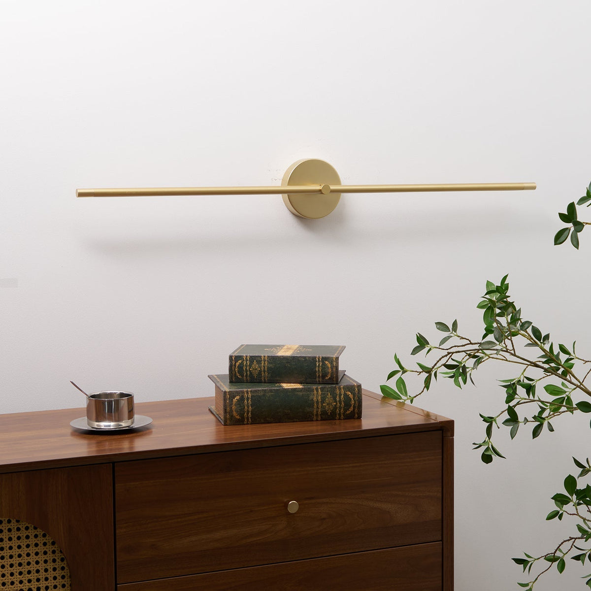 Rodo gold double-end wall light mounted above a wooden chest of drawers