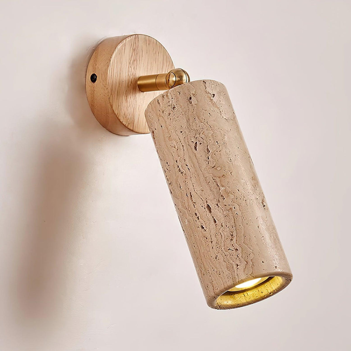 Sintra travertine wall light angled downwards, brass pivot joining the stone head to the wood backplate