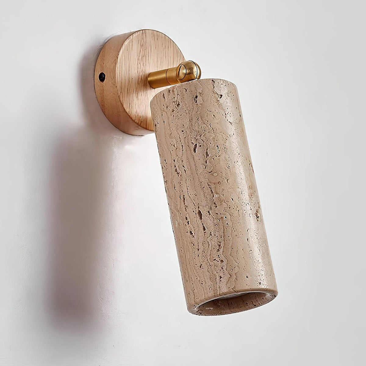 Sintra travertine wall sconce mounted on a plain white wall with the head tilted forwards