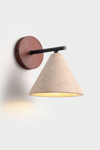 Marlo travertine wall light lit, shown at an angle against a plain pale background