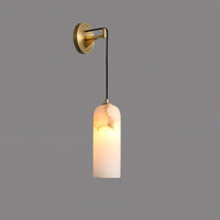 Uvella wall light lit on a plain grey wall showing the brass plate and slim cord
