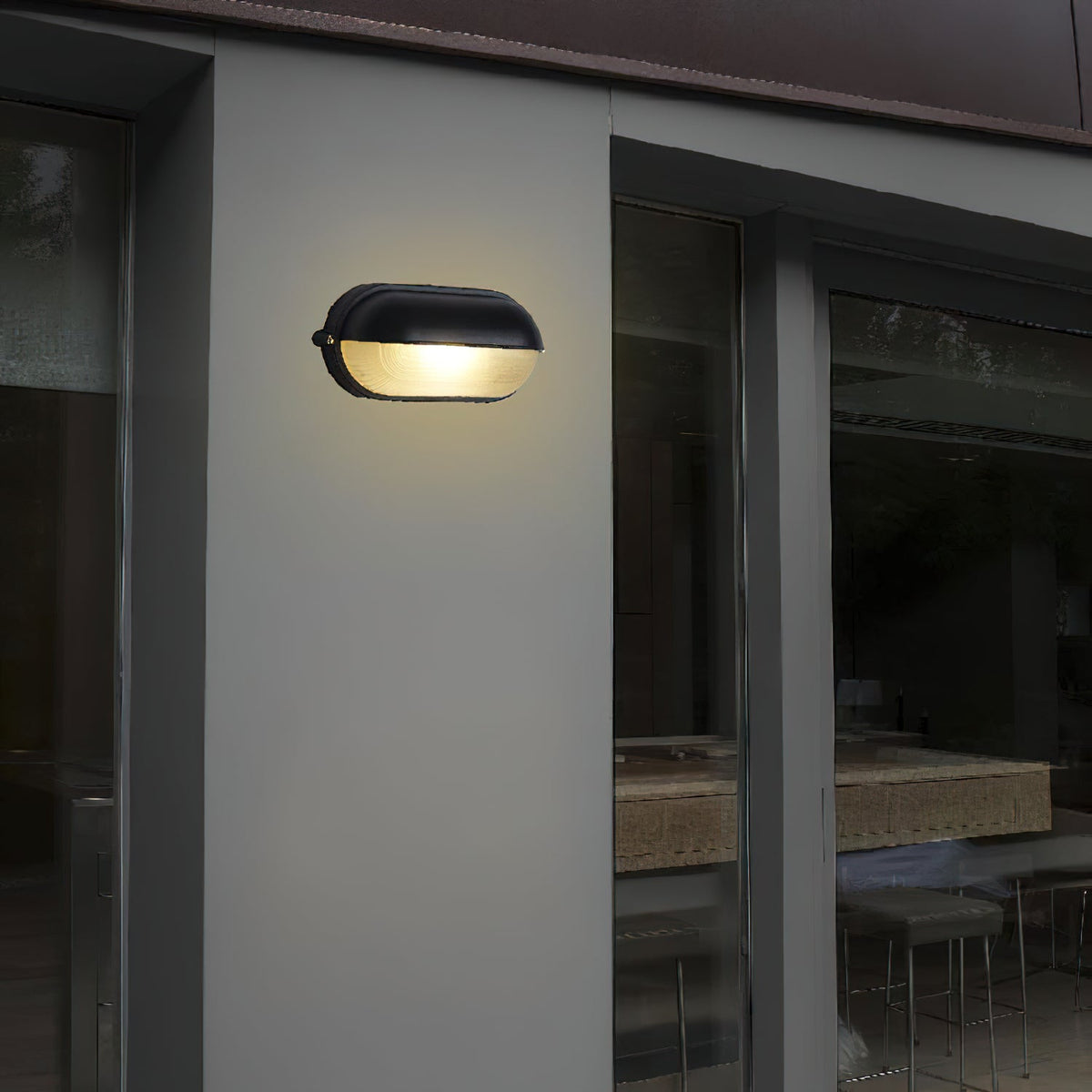 Verrow bulkhead wall light mounted on a pale rendered house wall beside sliding glass doors