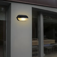 Verrow bulkhead wall light mounted on a pale rendered house wall beside sliding glass doors