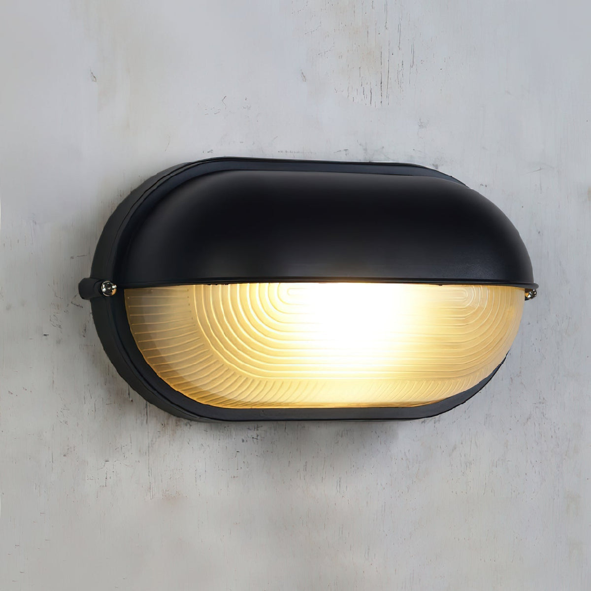 Close view of the Verrow wall light showing the black hood, side screws and ribbed glass diffuser