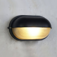 Close view of the Verrow wall light showing the black hood, side screws and ribbed glass diffuser
