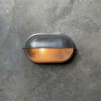 Estwin bulkhead wall light lit on a concrete wall showing the ribbed prismatic lens
