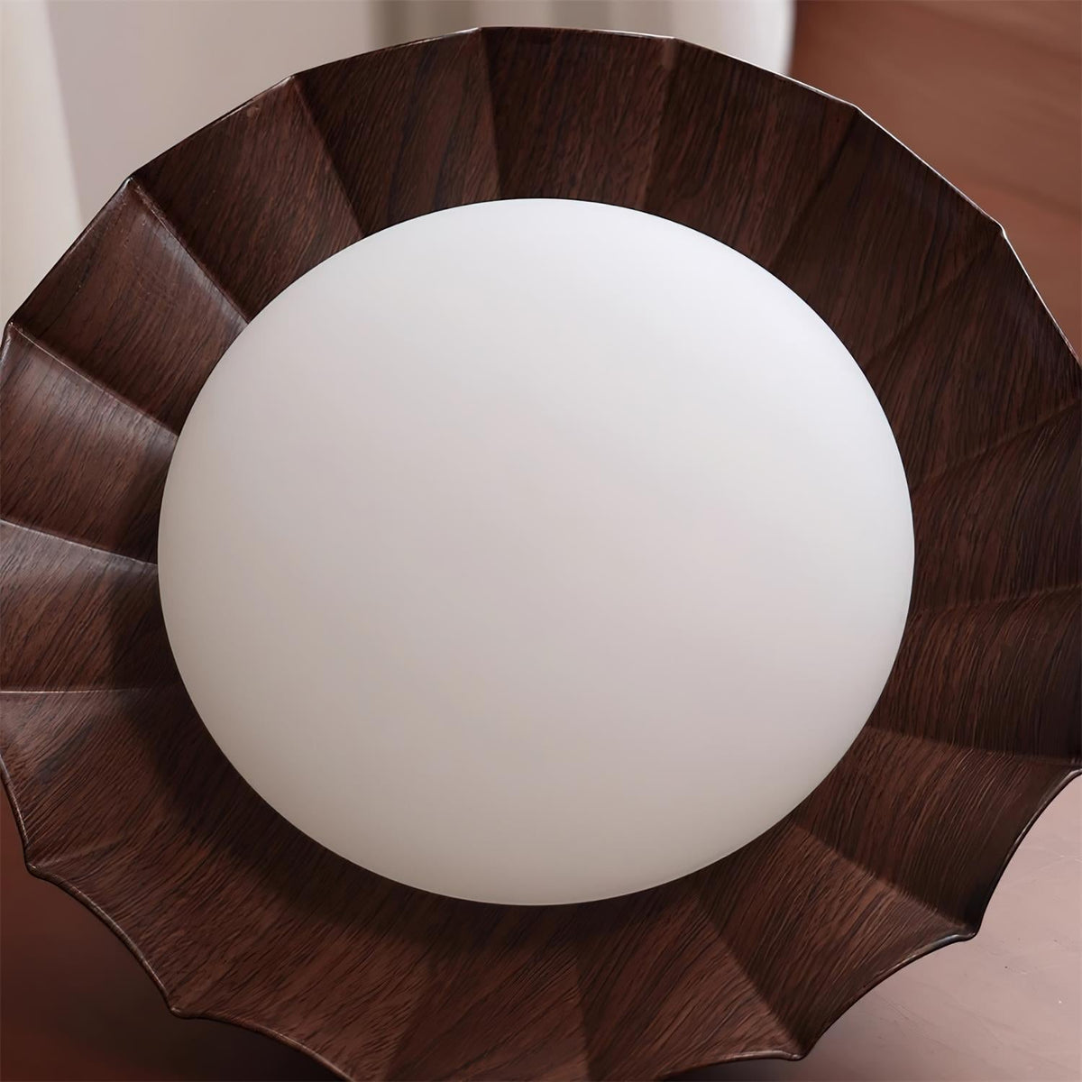 Underside view of the Wynto ceiling light showing the round opal diffuser framed by the walnut scalloped shade