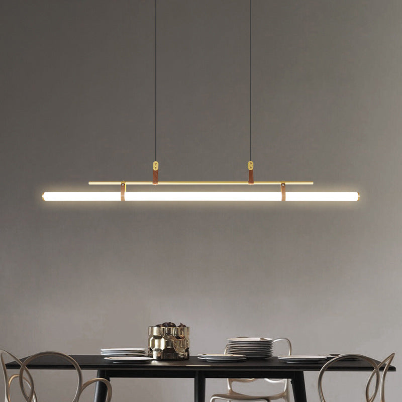 Inaro gold linear pendant hanging over a dark dining table