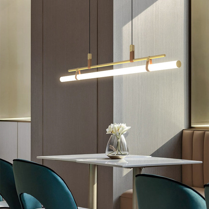 Inaro gold linear pendant lit above a marble cafe table