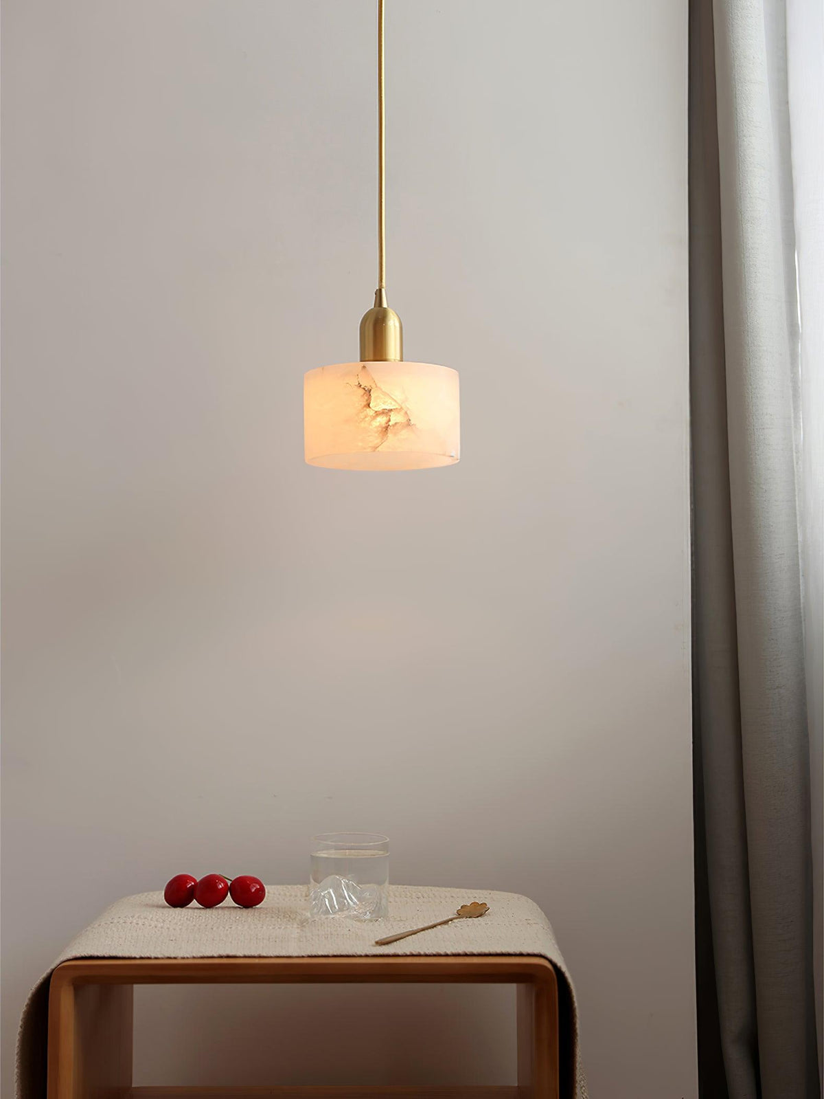 Nerva alabaster pendant hanging above a small timber side table in a bedroom corner