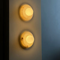 A pair of Harko marble wall sconces lit on a hallway wall