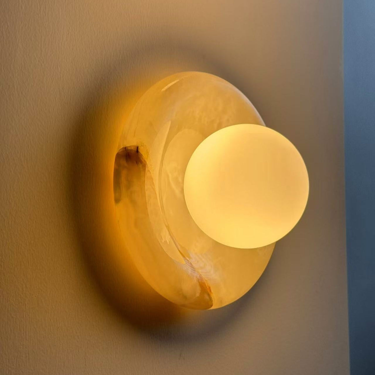 Harko marble wall sconce lit, casting a warm halo across the wall