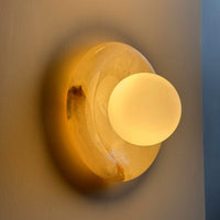 Harko marble wall sconce lit, casting a warm halo across the wall