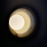 Harko marble wall sconce glowing against a dark wall