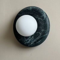 Angled view of the Avilo green marble sconce showing the rounded stone edge and offset globe