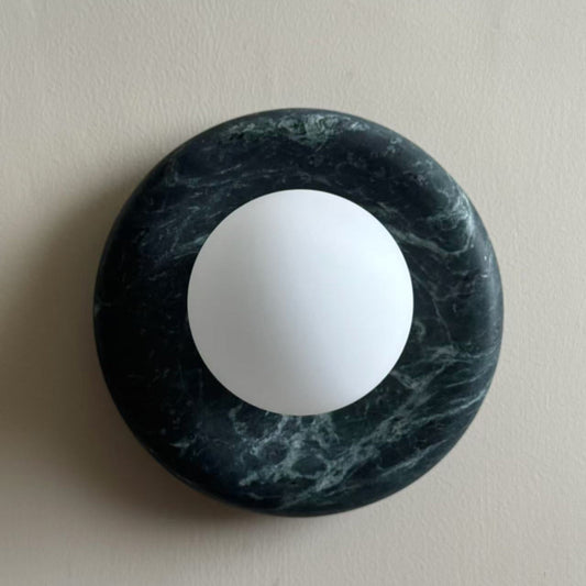 Avilo dark green marble wall sconce with a white glass globe on a plain wall