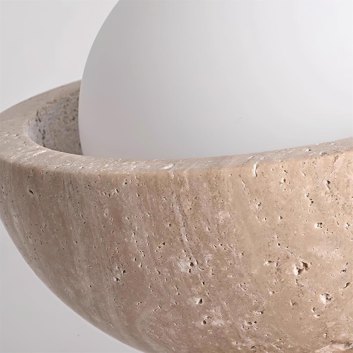 Close-up of the travertine rim and opal glass globe on the Isven ceiling light