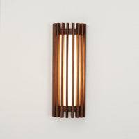 Neyro walnut wall light mounted on a plain wall and lit, showing the vertical bands of light